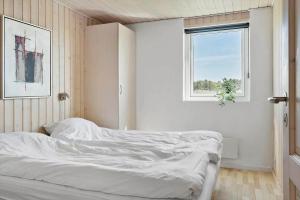 a white bedroom with a bed with a window at 115-Harboore-Strandvejen-164 in Harboør