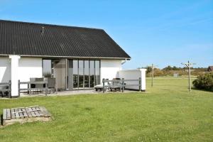 a white building with a picnic table and benches in a yard at 115-Harboore-Strandvejen-164 in Harboør