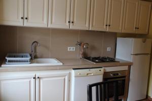 a kitchen with white cabinets and a sink and a refrigerator at La Petite Maison in Orgueil