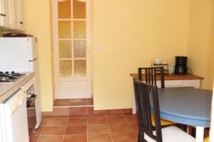 a kitchen with a table and a table and a door at La Petite Maison in Orgueil +2 photos