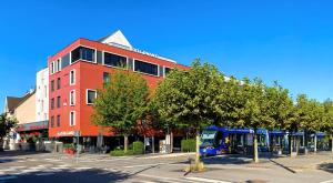 a blue bus parked in front of a red building at The Originals Boutique, Hôtel d'Alsace, Strasbourg Sud in Illkirch-Graffenstaden