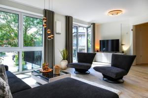 a living room with a couch and chairs and a tv at Wellenzauber in Kellenhusen