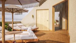 a room with chairs and umbrellas on a deck at Hotel Ben Marsalforn, Affiliated by Meliá in Marsalforn