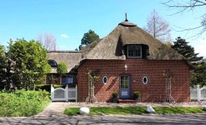 a large red brick house with a thatched roof at Sky & Sand Homes Sturmmöwe I Reetdach-Refugium mit Parkgarten in SPO in Sankt Peter-Ording