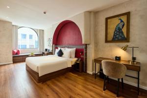 a hotel room with a bed and a desk and a chair at Kin Hotel Onsen Edition in Ho Chi Minh City