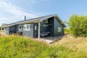 a blue house with a deck in a field at 528-Lemvig-Stranden-22 in Lemvig