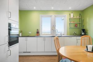 una cucina con mobili bianchi, un tavolo e una finestra di G147-Lemvig-Syrenvej-47 a Lemvig Altre 17 foto