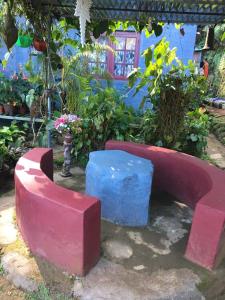 a red bench and a blue stool in a garden at Periyar Cottage in Munnar