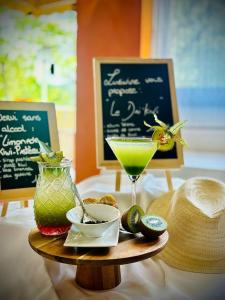 a table topped with a drink and a plate of food at Villa Borghese, The Originals Relais in Gréoux-les-Bains