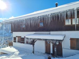 a house covered in icicles with snow on it at Gîte de l Auguille in Megève