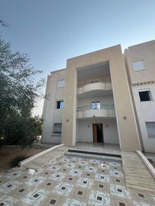 a large white building with a courtyard in front of it at Apartment de luxe avec balcon in Houmt Souk