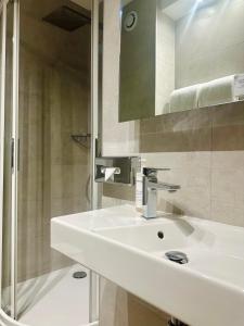 a bathroom with a white sink and a shower at Villa Borghese, The Originals Relais in Gréoux-les-Bains