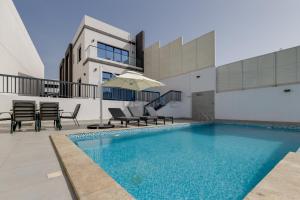 フジャイラにあるCoastal Escape with Private Pool, Breathtaking Sea And Mountain Views, Near Al Aqah Beach - Al Dana Island, Fujairah by Deluxe Holiday Homesの建物の隣にスイミングプール(椅子、パラソル付)があります。