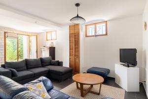 Una sala de estar con un sofá y un televisor. en Appartement 70m2 à 10 minutes de Lyon adapté PMR, en Saint-Genis-Laval