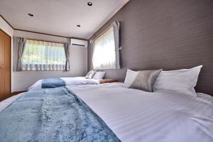a large white bed in a room with two windows at TOCORO Mt Fuji Shizuku in Fujikawaguchiko