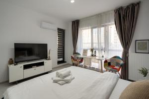 a bedroom with a bed with a television and chairs at Plaza Residence Studio 197 in Bucharest
