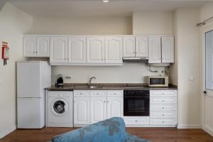 una cucina con mobili bianchi, un lavello e una lavastoviglie di Golden Star AV a Funchal Altre 4 foto