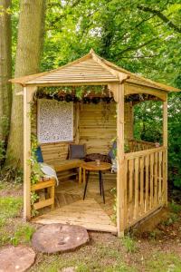 a wooden gazebo with a bench and a table at Sunset Lodge in Kingham