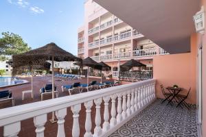 un balcón de un hotel con sillas y sombrillas en Parque dos Reis Apartment 4 A, en Monte Gordo