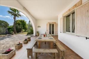 an outdoor dining room with a wooden table and a large window at Tenuta Gianfredi by BarbarHouse in Casarano