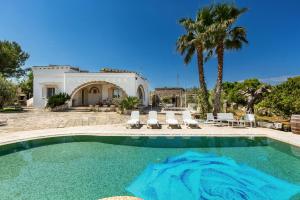 a swimming pool in front of a house with a palm tree at Tenuta Gianfredi by BarbarHouse in Casarano
