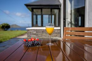 a glass of wine and a bowl of fruit on a table at Skellig Bay Cottage in Waterville