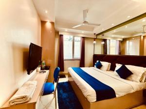 a bedroom with a bed and a desk and a television at Majesta stays pitampura in New Delhi