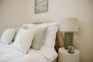 ウッチにあるApartamenty Łódź Agosto Sky Premium Manufaktura Parking Gratis FVのベッド(白い枕、テーブルの上のランプ付)