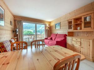 Una sala de estar con una mesa de madera y un sofá rojo en Luminosité et espace, 2 pièces, centre village, proche pistes, ascenseur - FR-1-304-14, en La Clusaz