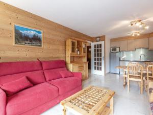 Una sala de estar con un sofá rojo y una cocina. en Luminosité et espace, 2 pièces, centre village, proche pistes, ascenseur - FR-1-304-14, en La Clusaz