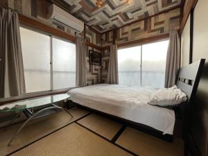 a bedroom with a bed and two windows at Haneda Artistic House in Tokyo +46 photos