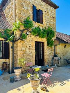 ein Steinhaus mit einem Tisch und Stühlen davor in der Unterkunft Laugerie Basse Gites Charming Pigeonnier Gite in Berbiguières