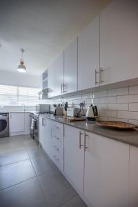 a large white kitchen with white cabinets and appliances at Chic apartment with a beautiful view in Cape Town