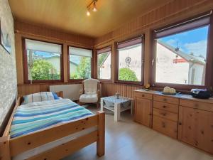 a bedroom with a bed and a chair and windows at Storchenblick in Sieverstedt - ebenerdige FeWo in ruhiger Umgebung in Sieverstedt