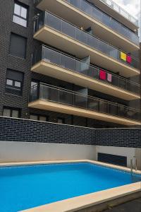 an apartment building with a swimming pool in front of it at Luxury Beachfront Family Apartment in La Pineda