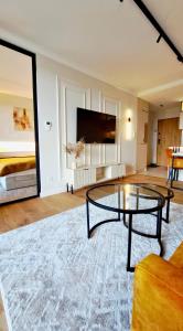 a living room with a glass table and a tv at 9th Floor Apartament 95 - obok galerii echo in Kielce