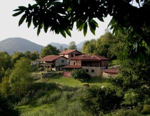 an old house in a field with mountains in the background at La Casona de Con in Mestas de Con