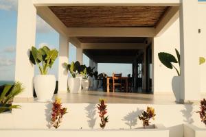 a porch with white vases with plants on it at Villa Kweli - Private Ocean Front Villa in Tongoni