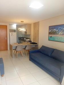 un soggiorno con un divano blu e una cucina di Flat Beira Mar - Carneiros Beach Resort a Tamandaré