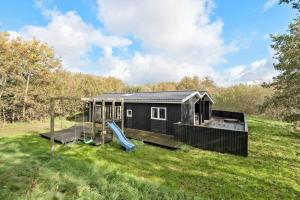 a black tiny house with a playground in a field at FAN049-Fano-Larses-Toft-31 in Fanø
