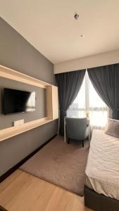 a bedroom with a bed and a tv and a chair at SS Homestay by Stella in Kota Kinabalu