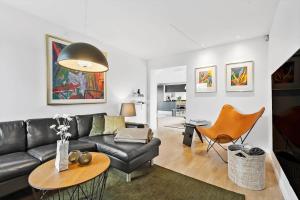 凡岛FAN006-Fano-Gogevej-43的客厅里有一张黑色皮沙发和一张桌子