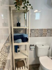 a white bathroom with a toilet and a plant at Casa Pura Vida in Tarajalejo
