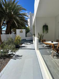 a patio with a table and chairs and palm trees at Casa Pura Vida in Tarajalejo