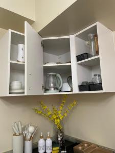 a kitchen with white cabinets with dishes and utensils at Avida Towers in Davao City