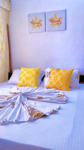 a bed with yellow and white sheets and pillows at Marthe Appartement in Cotonou