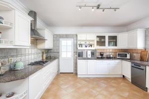 eine weiße Küche mit weißen Schränken und Geräten in der Unterkunft Villa Botanica in Canhestros