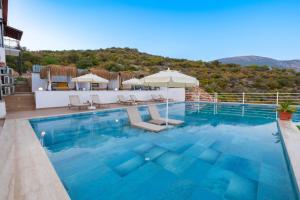 a pool with chairs and umbrellas on a building at Hamarat Otel in Kaş