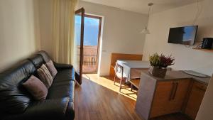 a living room with a black leather couch and a table at Panorama Dolomiti in San Vigilio Di Marebbe