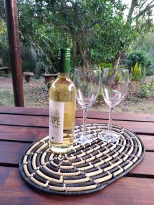 a bottle of wine and two wine glasses on a table at Bush Beach Safari Accommodation in Jeffreys Bay